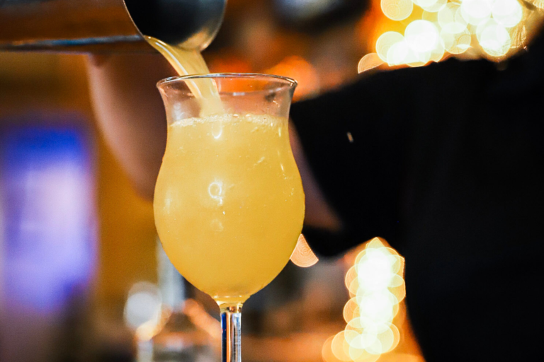 A person pouring an orange-colored beverage into a glass.